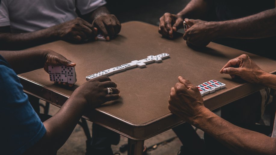 Four people playing dominoes around a table