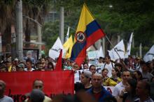 People marching, one holding big Colombian flag